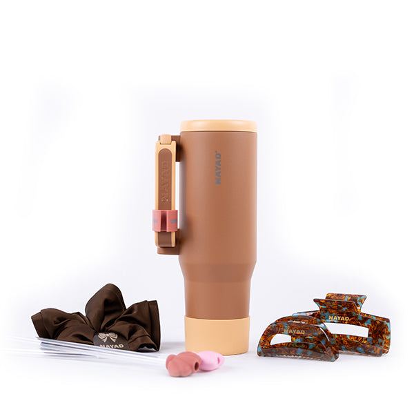Brown tumbler with accessories on a white background