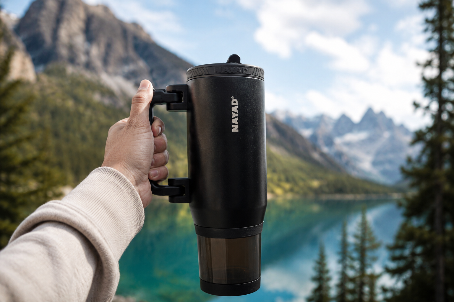 man hand holding out a black hydrostash tumbler in front of a sceneric nature view