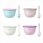 Four pastel-colored baby stainless steel salad bowls with matching spoons, arranged in a 2x2 grid on a white background. The sets feature light blue with pink lids, light pink with beige lids, off-white with green lids, and light purple with pink lids.