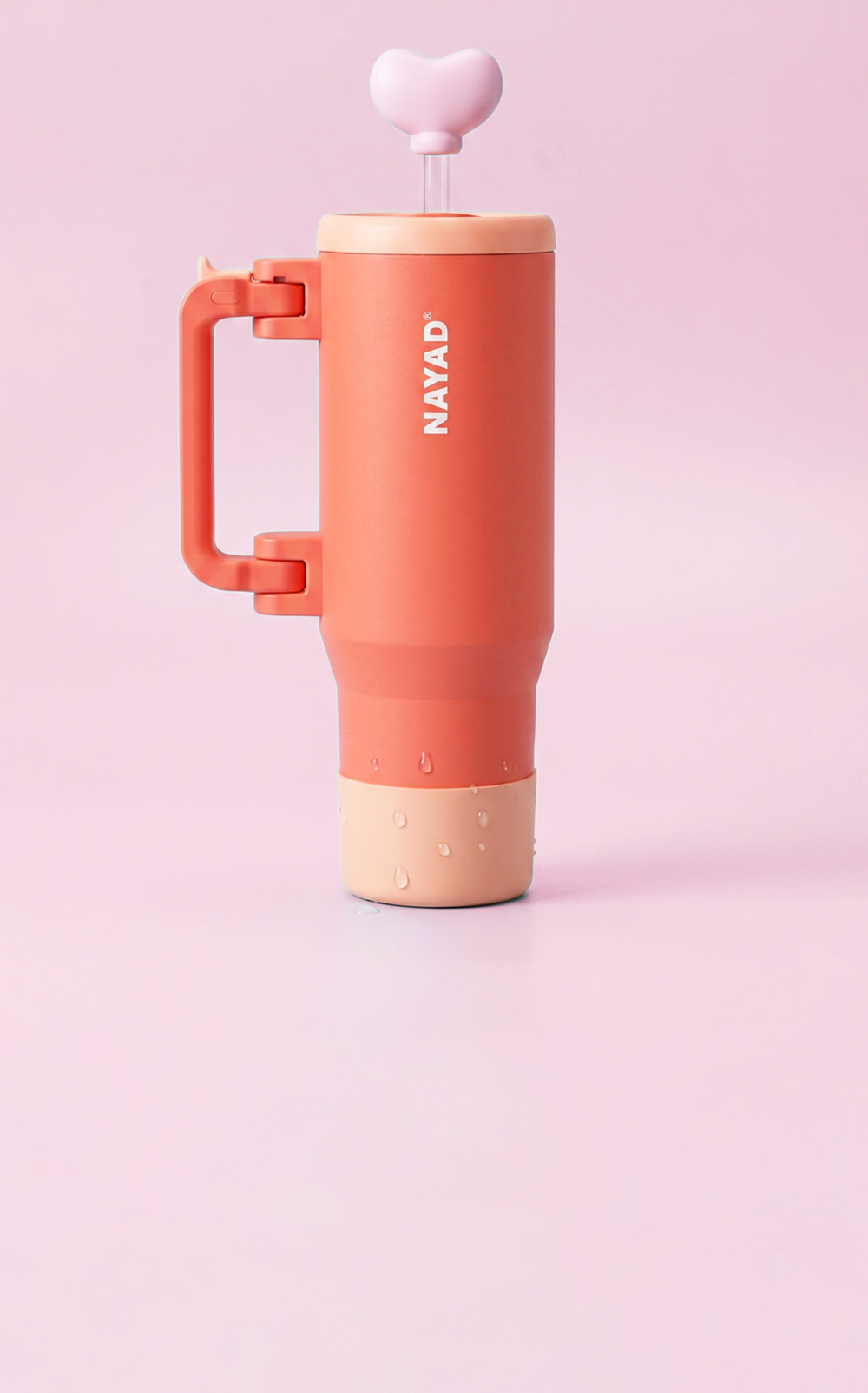 Coral-colored tumbler with beige base and handle on a pink background