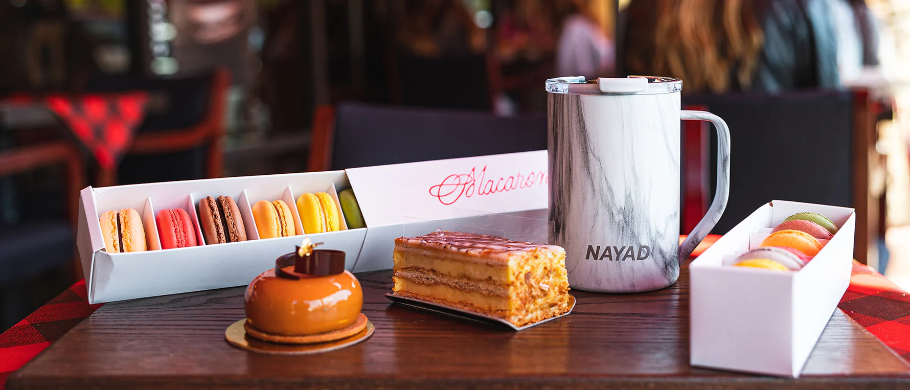 Dessert set with macarons, cake, and a mug on a table in a restaurant setting.