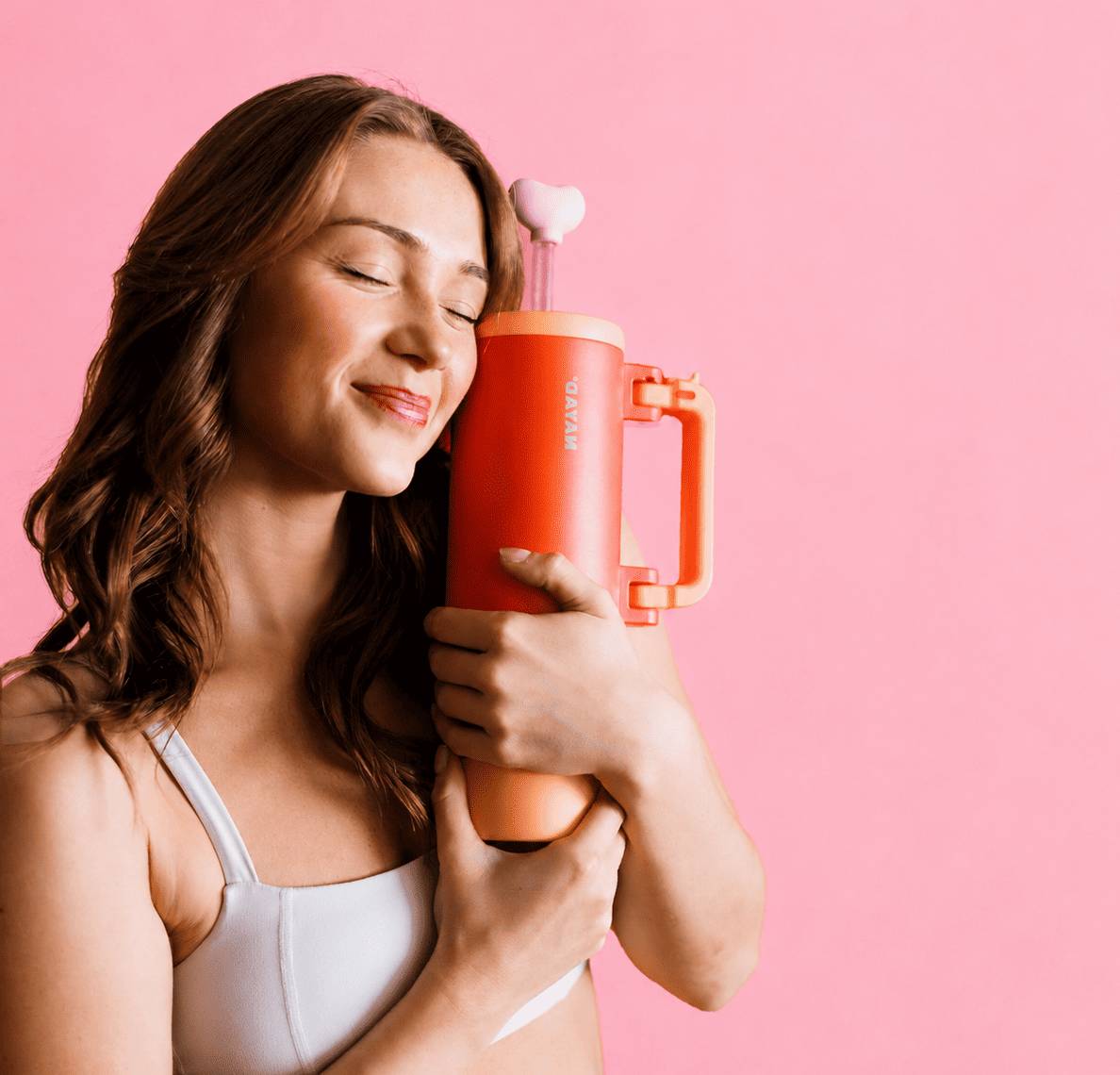 Woman holding a red and orange nayad hydrocore bottle against a pink background