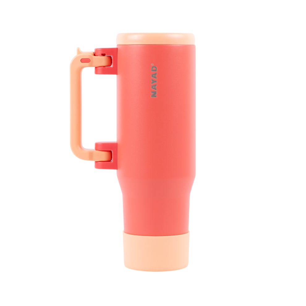 Coral-colored tumbler with a handle on a white background